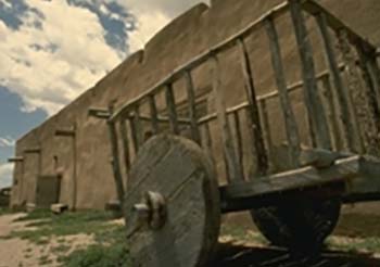 wood cart in front of adobe structure