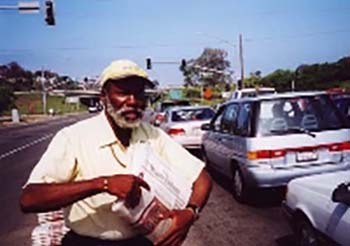 Man selling newspapers in traffic